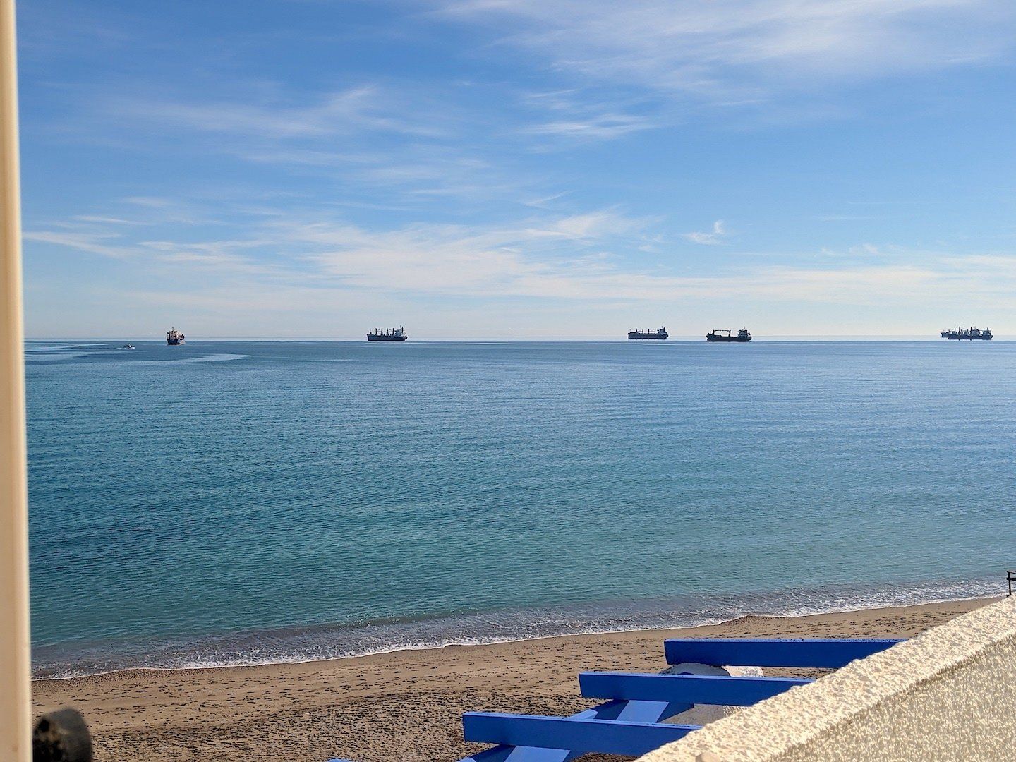 looking out from window over roof out to sea with ships on the horizon