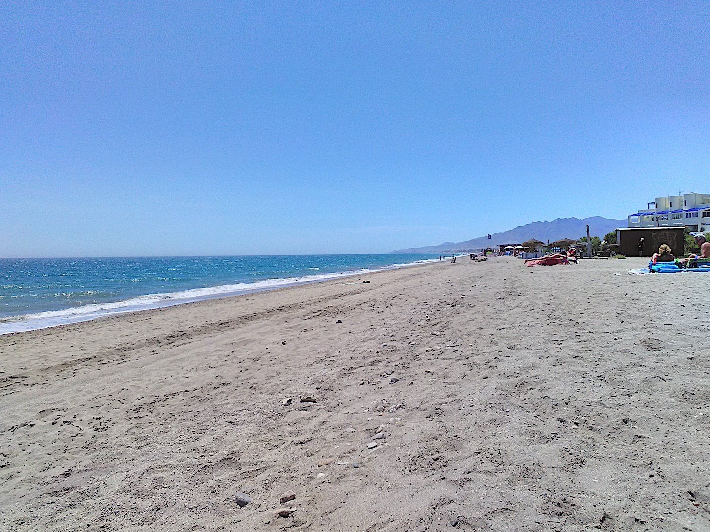 wide sandy beach with a few sunbathers to the right