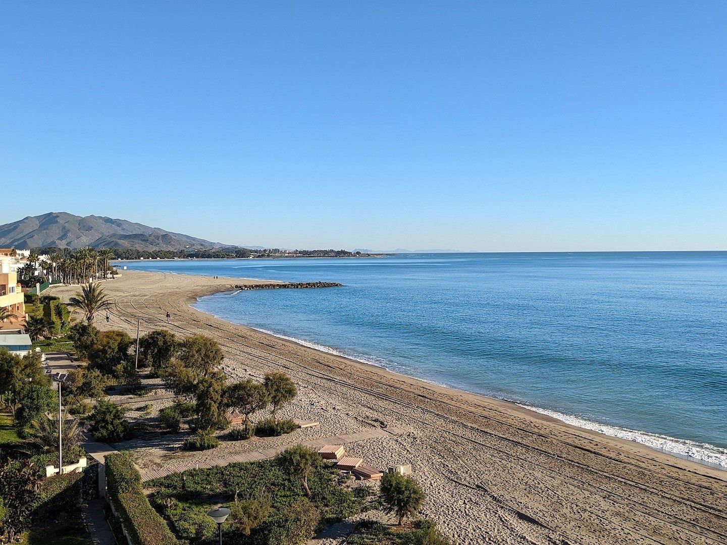 a lovely smooth looking widened beach with the mountains in the background