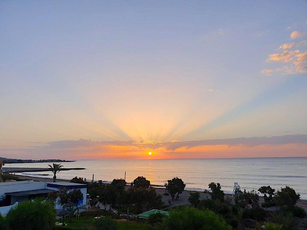 looking from the terrace across the beach and out to sea at sunrise and it looks like the sun is sending orange lazer beams into the sky