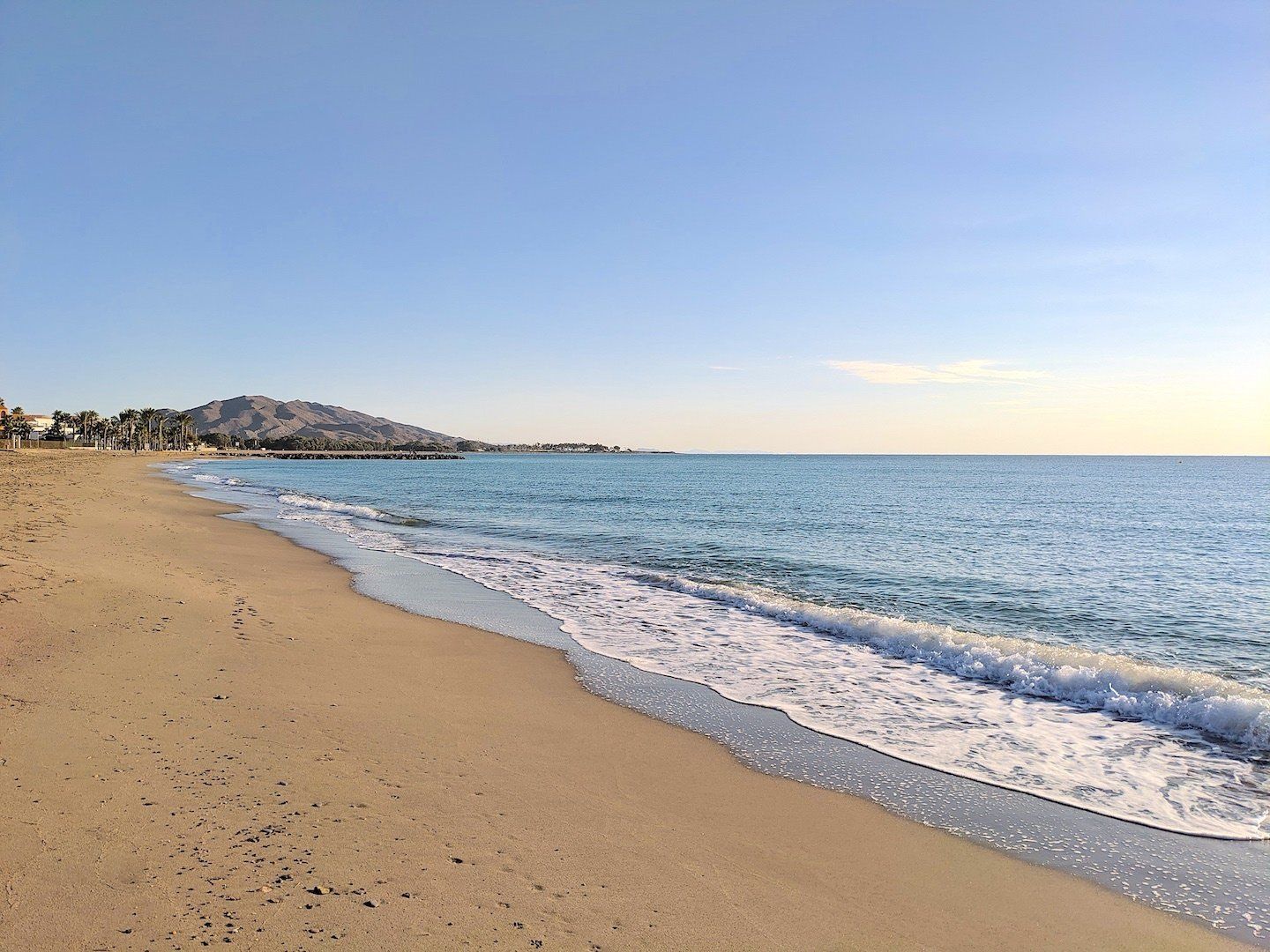 looking along the sandy shoreline with the mountain in the distance