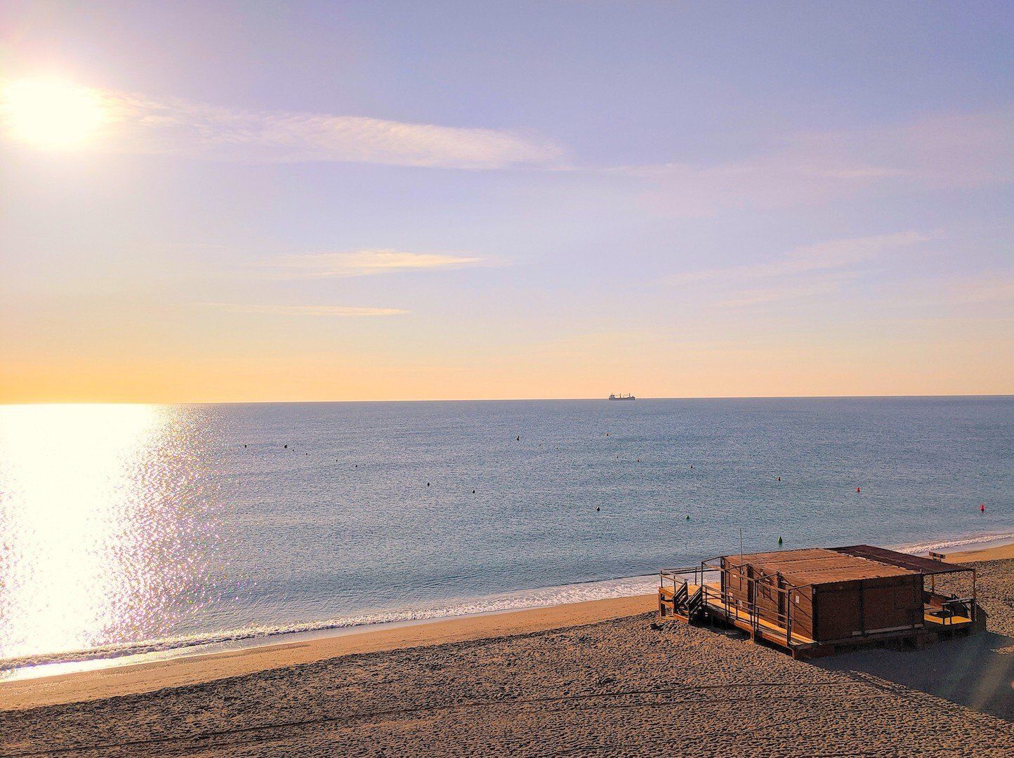 looking down onto beach and sea beyond at dusk  with a wooden shed in the bottom right hand corner on the sand