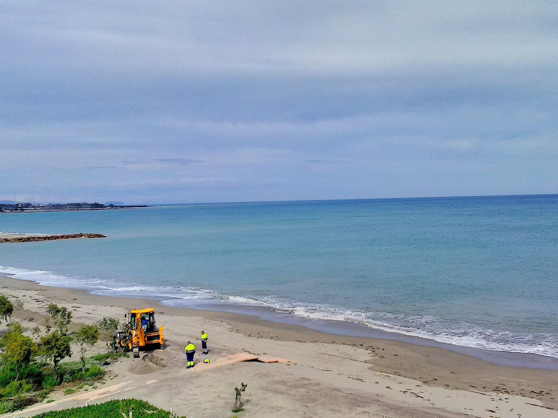 from a distance workmen are on the beach making repairs