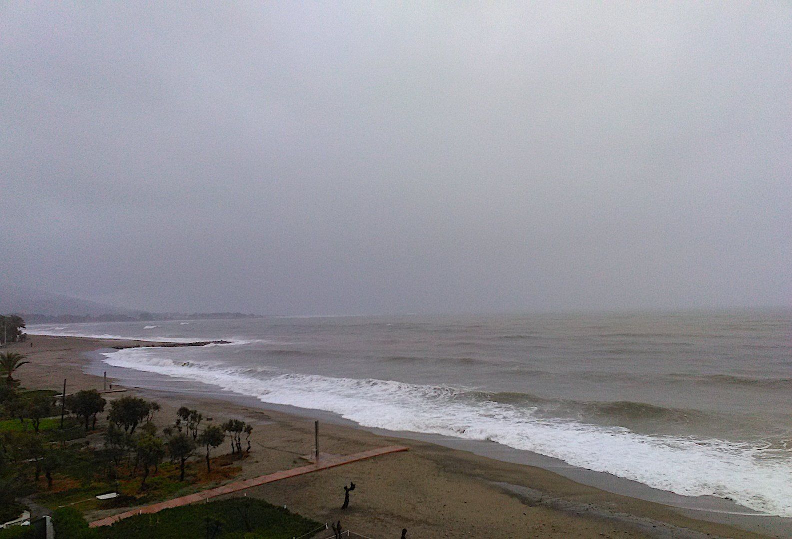 looking north the beach is in the middle of a storm and the seas are pounding onto the sand