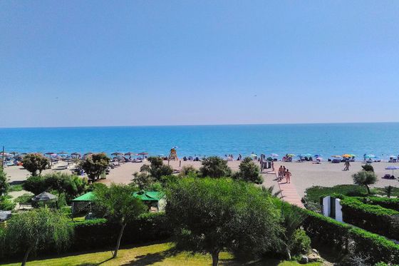 view from apartment mediterraneo of the naturist beach with people walking onto the beach naked