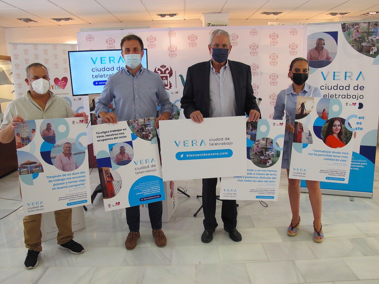 four people stood side by side dressed smartly holding up promo posters