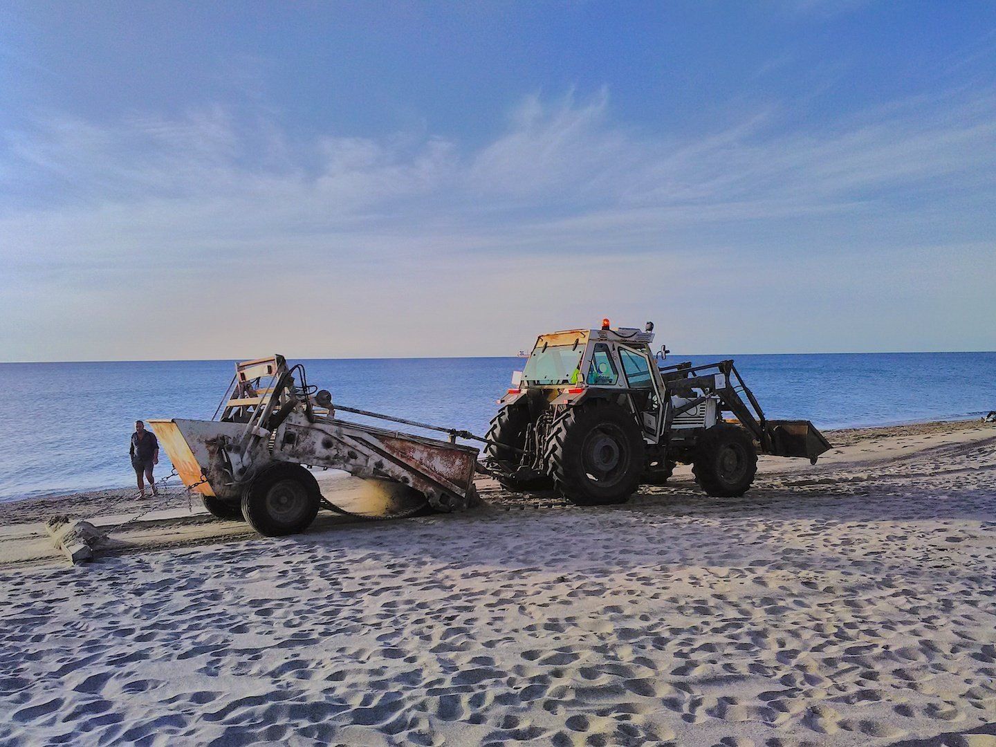 tractor pulling trailer driving across the beach