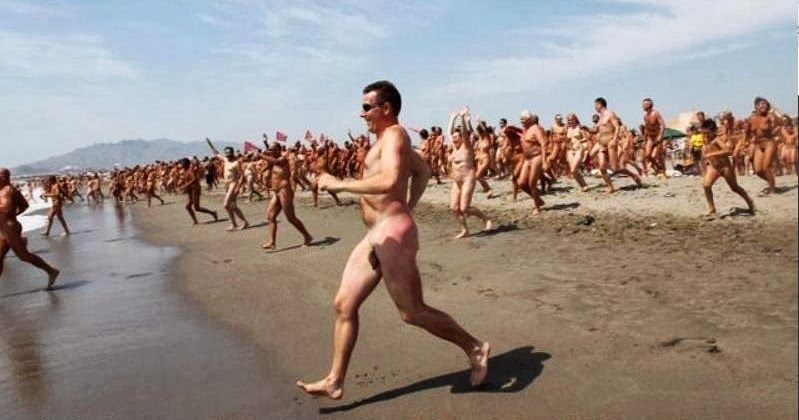 a huge crowd of naked people running into the sea