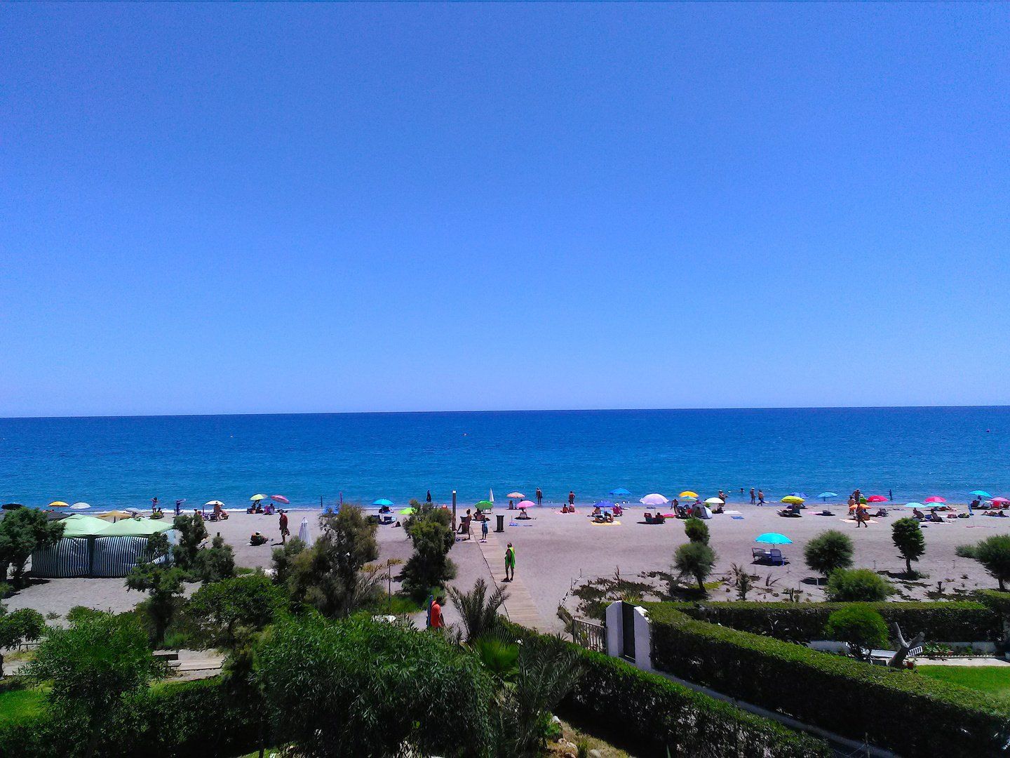 view from the terrace across the beach with lots of people there and out to sea