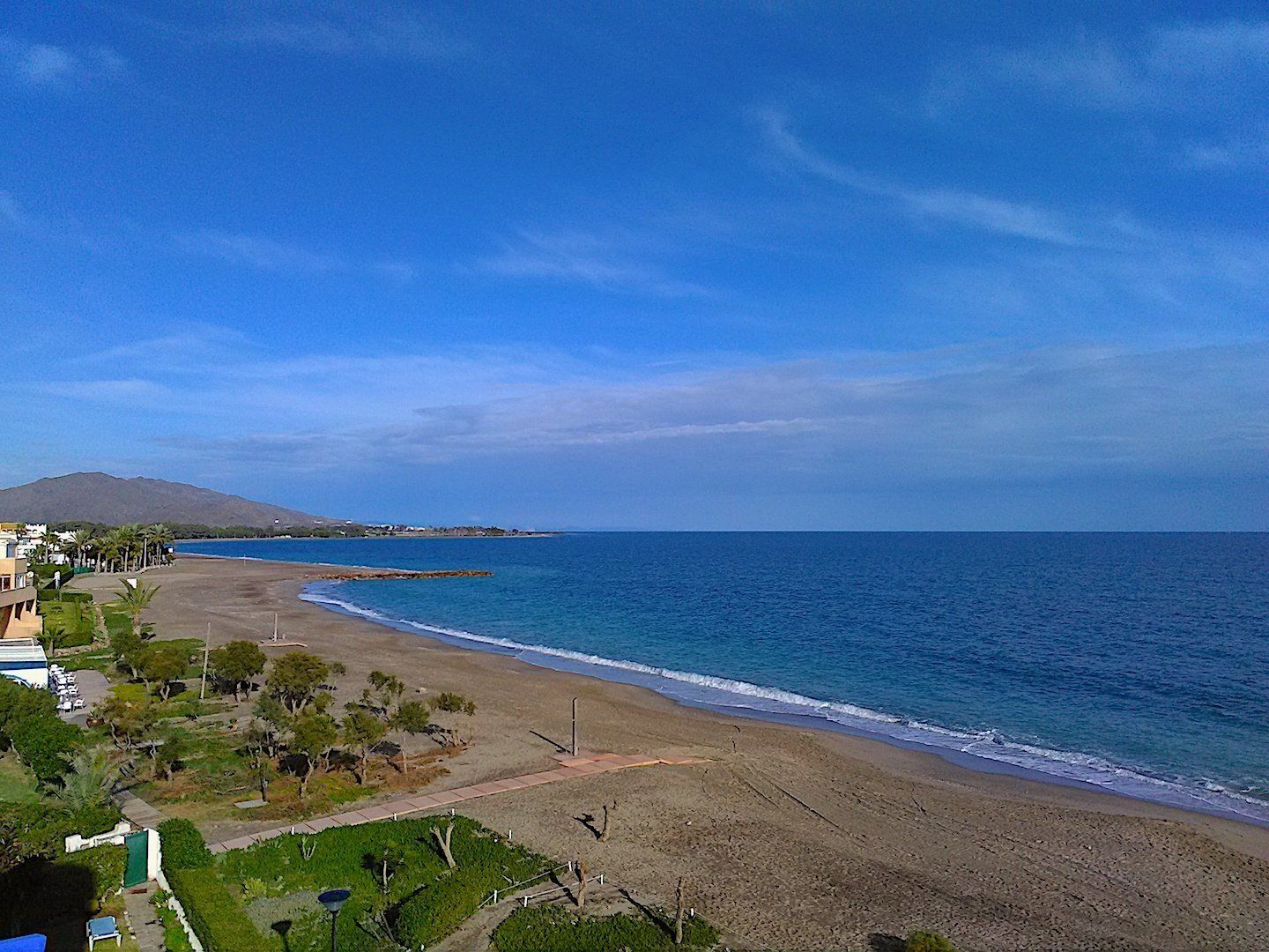 an empty beach on a winters day but it still looks warm because the sky and sea are blue