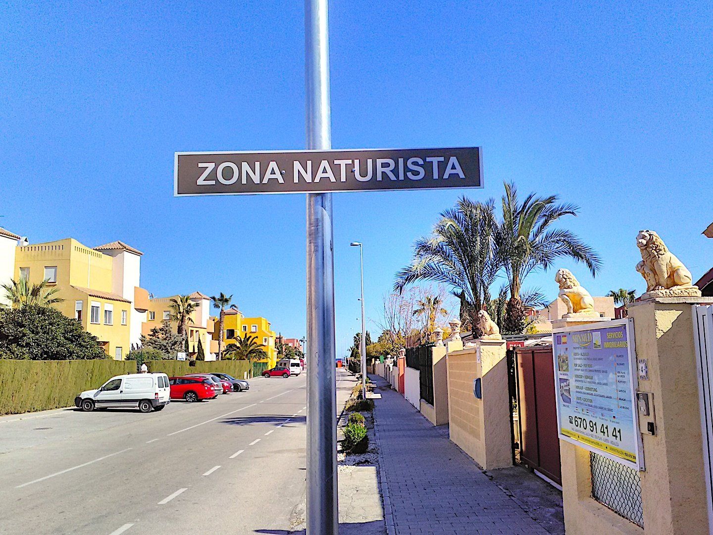 a street scene with a lamp post and a sign on it saying zona naturista