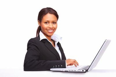 femme tailleur sourit en tapant sur ordinateur