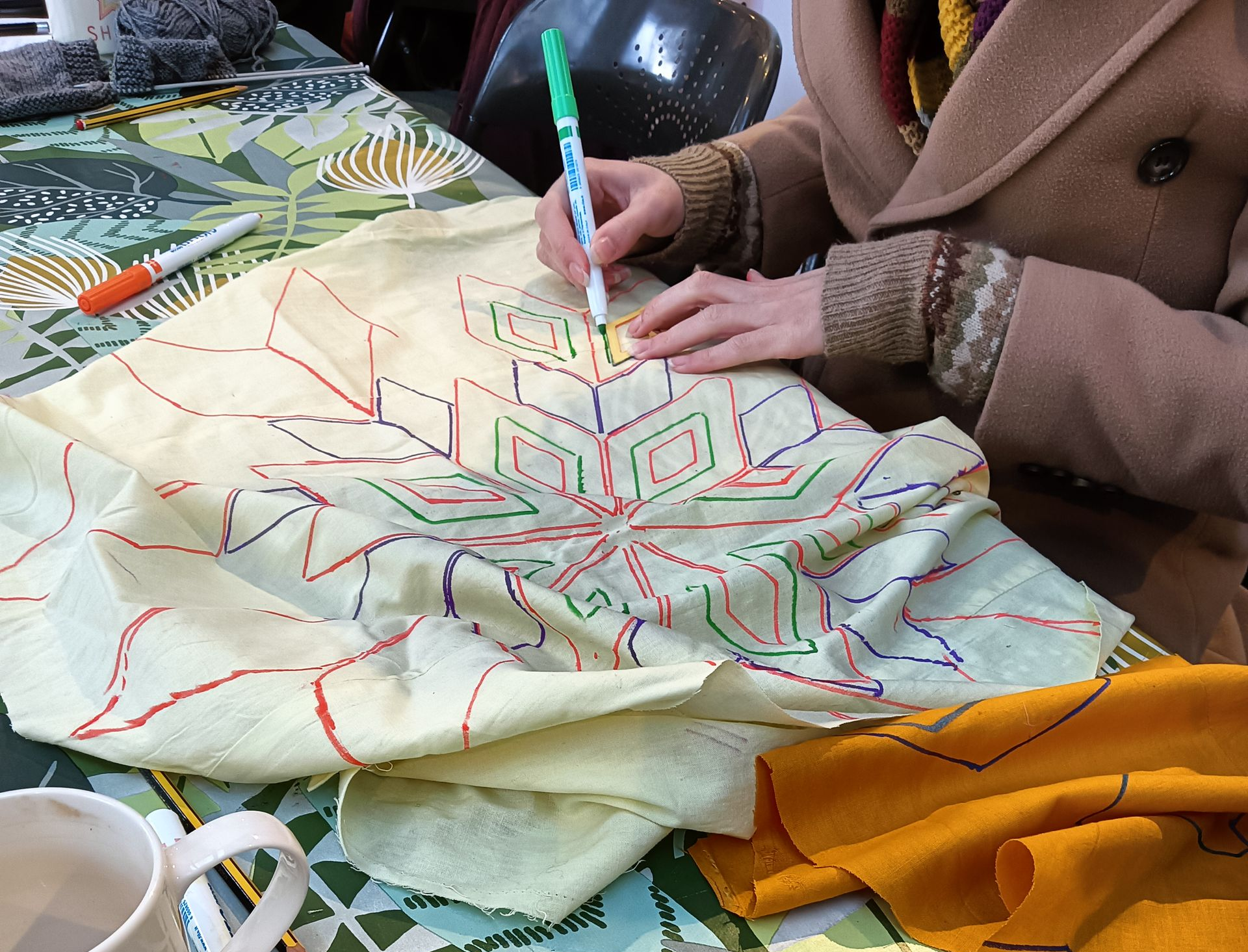 A hand using pens to create a deign on upcycled fabric