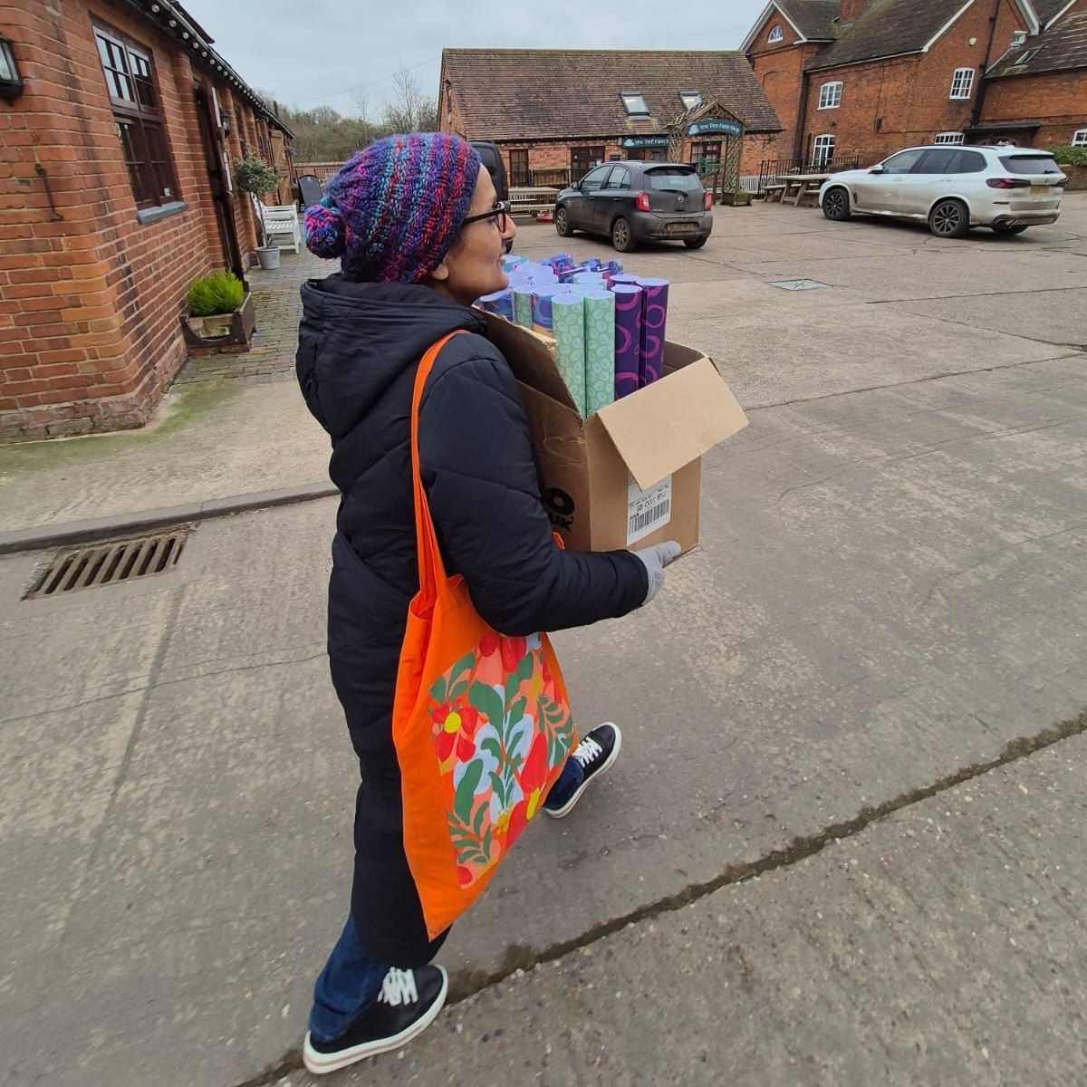 An image of Rakha Madahar carrying a box of luxury wrapping paper. Ranging from Geometric to floral designs.