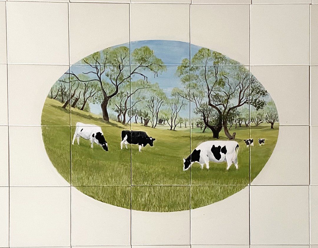 Hand painted tile mural feature of a field of cows by Gabrielle Dudley