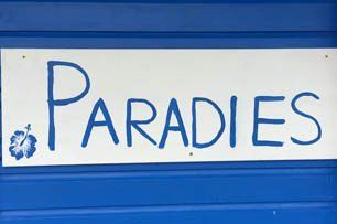 Das Wort Paradies, handgemalt blau auf weiß.