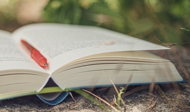 aufgeschlagenes Buch mit orangefarbenem Stift