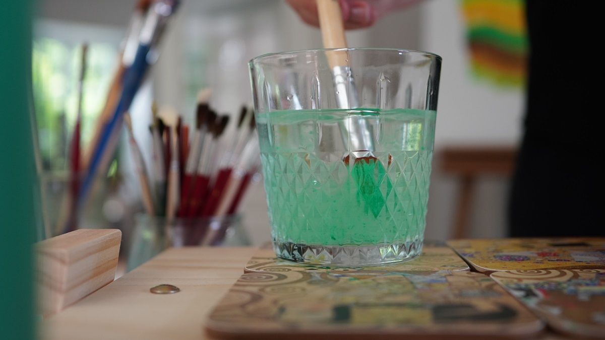 Pinsel mit Resten grüner Farbe in einem Glas mit hellgrünem Wasser - Praxis für Kunsttherapie Susanne Grön