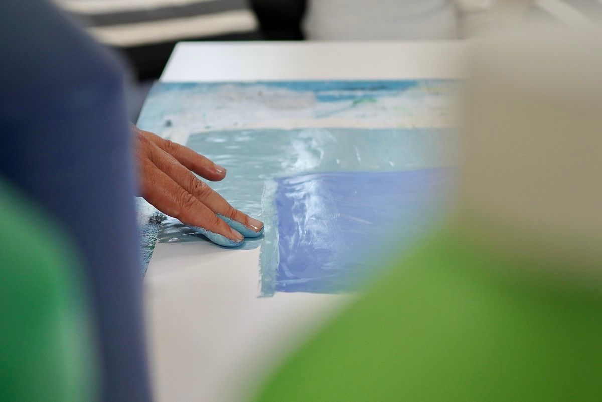 Eine Hand, die mit Fingern ein Bild malt mit verschiedenen Blautönen - Praxis für Kunsttherapie Susanne Grön in Zarrentin.