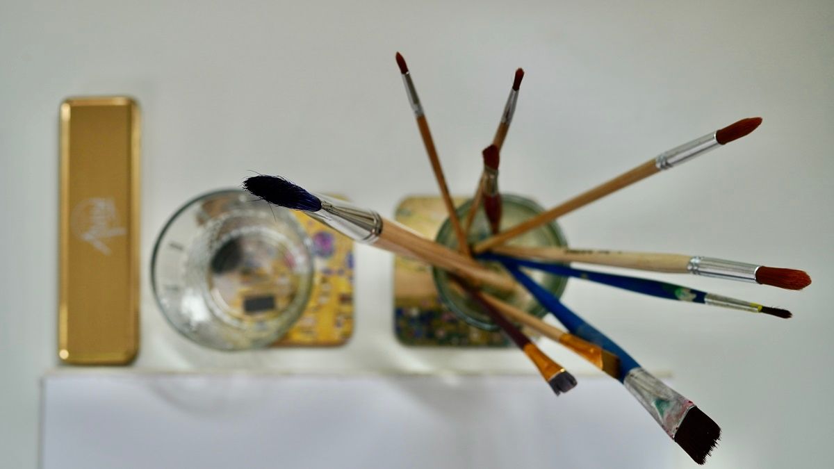 Draufsicht auf verschiedene Pinsel im Glas und daneben ein Wasserglas - Kunsttherapie Susanne Grön - Zarrentin