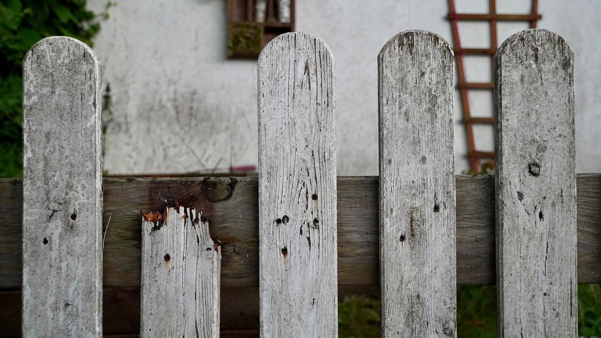 Verwitterter grauer Holzzaun, eine der Latten ist abgesplittert - - Praxis für Kunsttherapie Susanne Grön in Zarrentin.