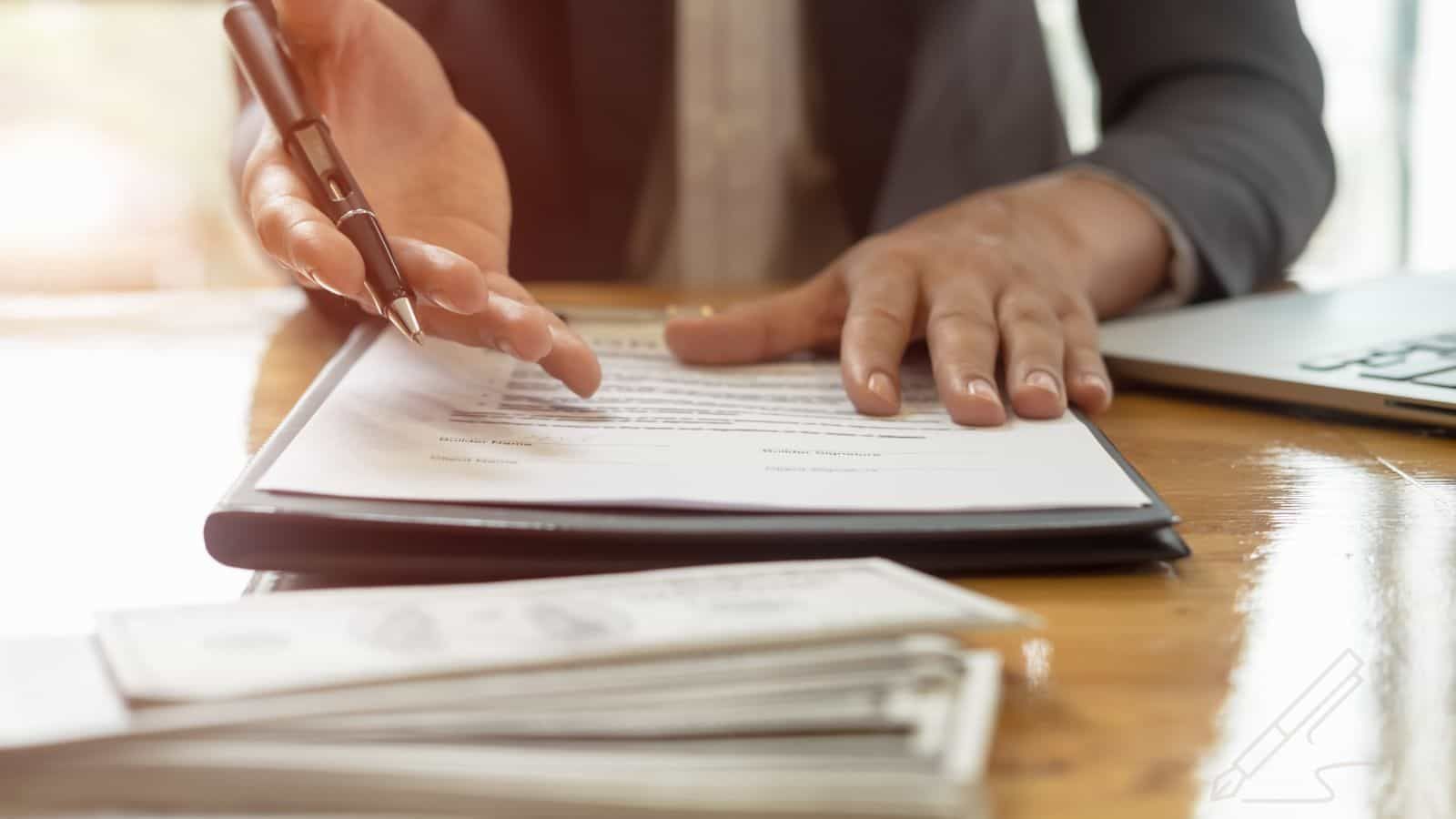 A man a desk with paperwork reaching out his hand