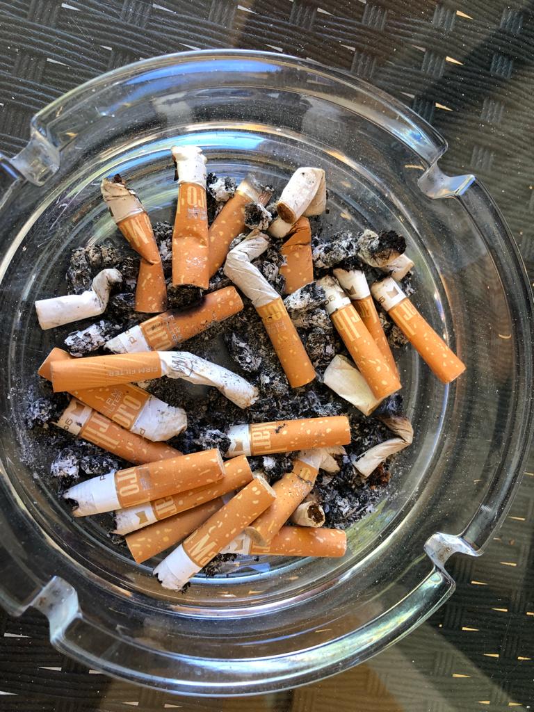 Ein  Aschenbecher voll mit Zigarettenstummeln auf einem Tisch