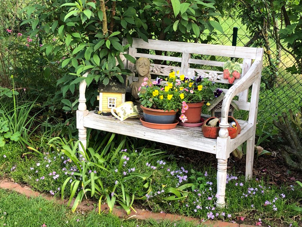 Bank mit Blumen und Deko Bank mit Blumen und Dekoration in einem Beet