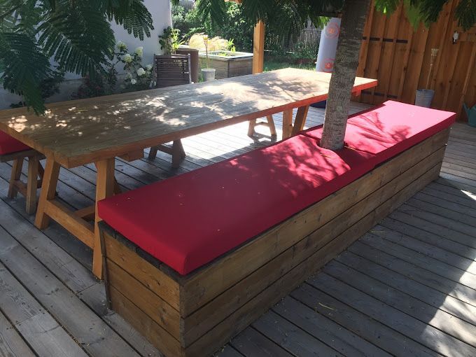 Long coussin d'assise rouge sur mesure pour habiller un banc en bois intégré autour d'un arbre dans le jardin.
