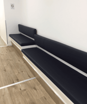 Banquettes murales noires minimalistes installées dans un couloir aux murs blancs épurés.