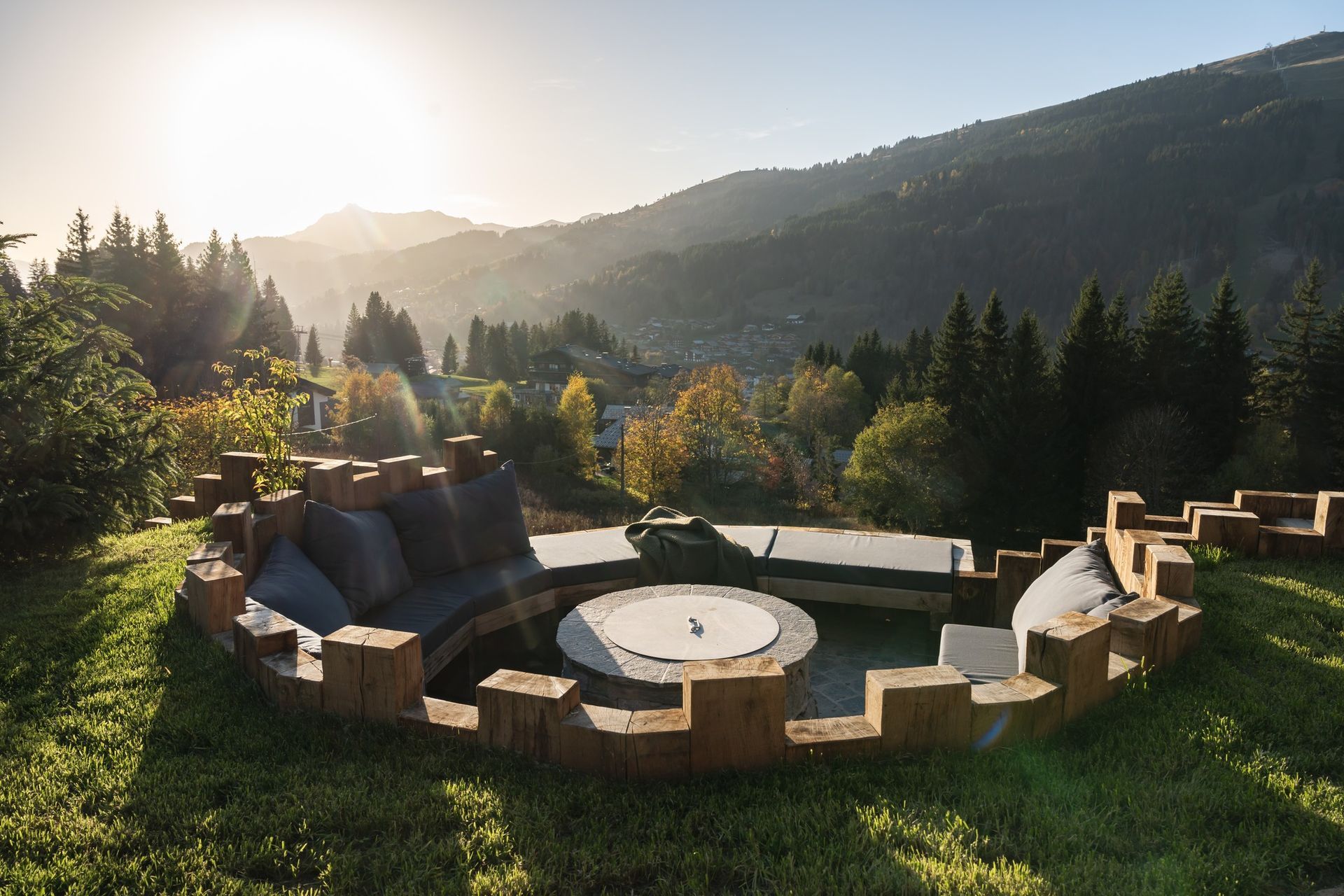 Coussins extérieurs foncés sur mesure pour un salon de jardin circulaire en pierre avec vue sur les collines.