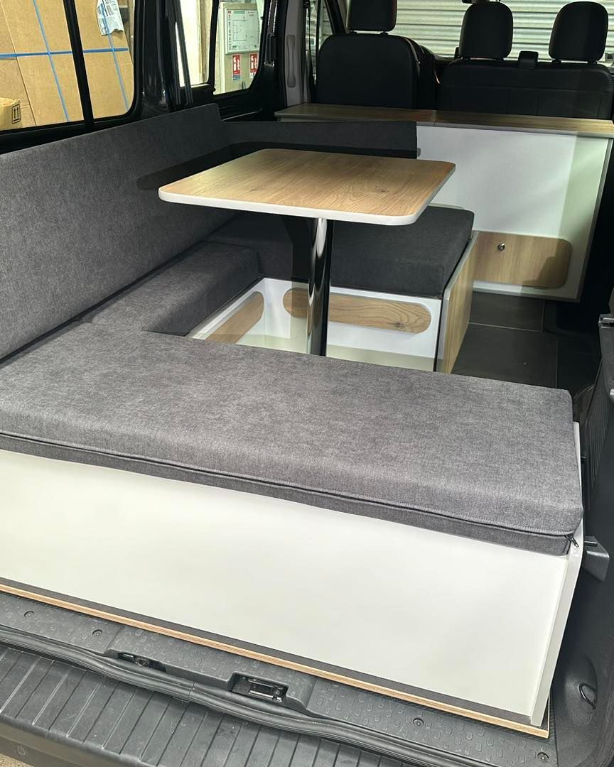 Banquette sur mesure gris clair avec table dépliable dans van aménagé, vue arrière – coussin fourgon Mousse et Confection