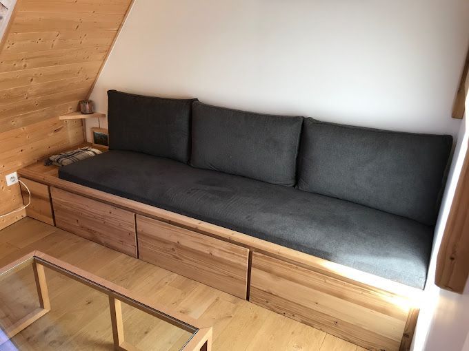 Coussins d'assise et de dossier noirs sur mesure pour une banquette en bois avec rangements intégrés.