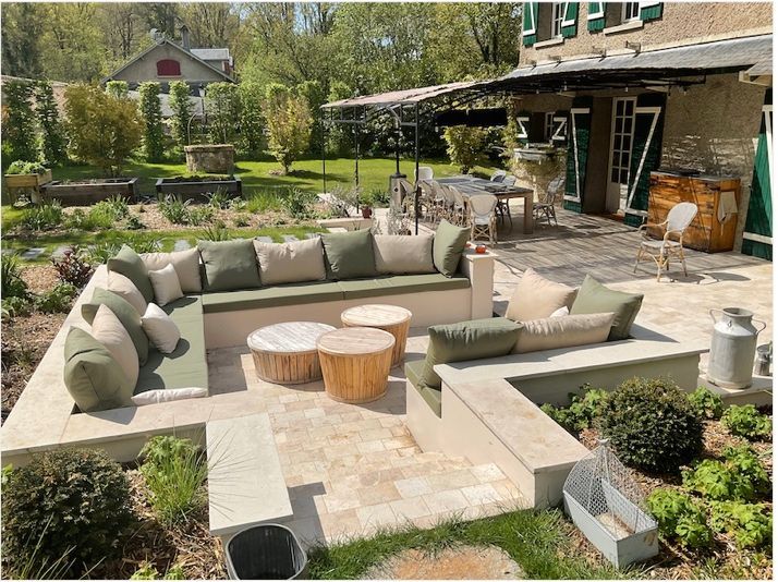 Coussins extérieurs beiges et verts sur mesure pour un grand salon maçonné en U dans un jardin paysager.