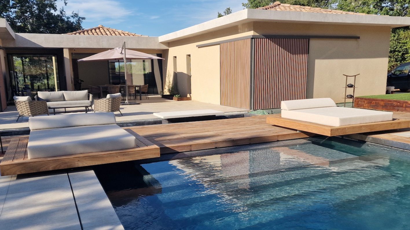 Vue d'ensemble d'une piscine moderne avec bains de soleil intégrés sur une terrasse en bois et béton.