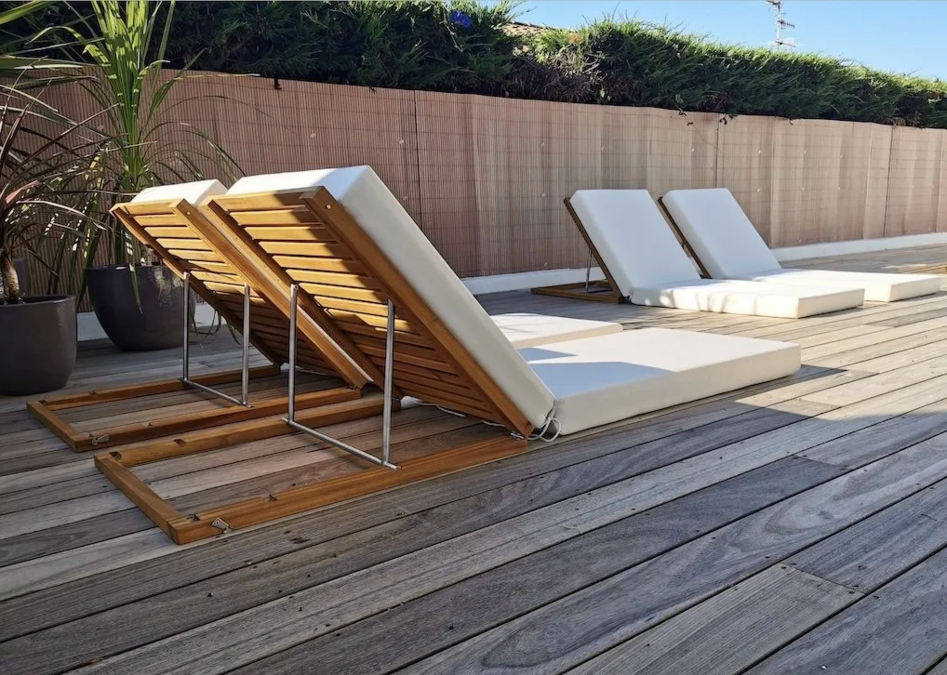 Matelas de bain de soleil beiges articulés sur mesure pour des transats en bois et métal.
