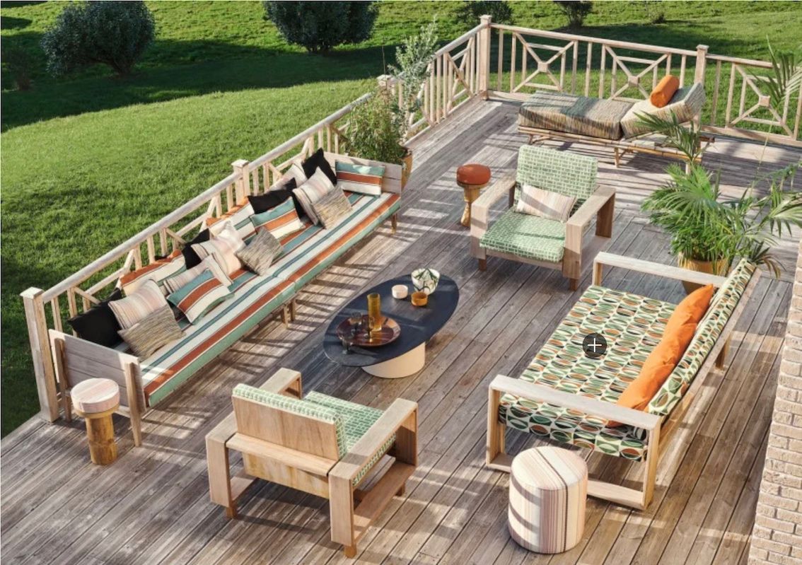 Terrasse en bois aménagée avec de larges banquettes extérieures et des coussins à motifs colorés.