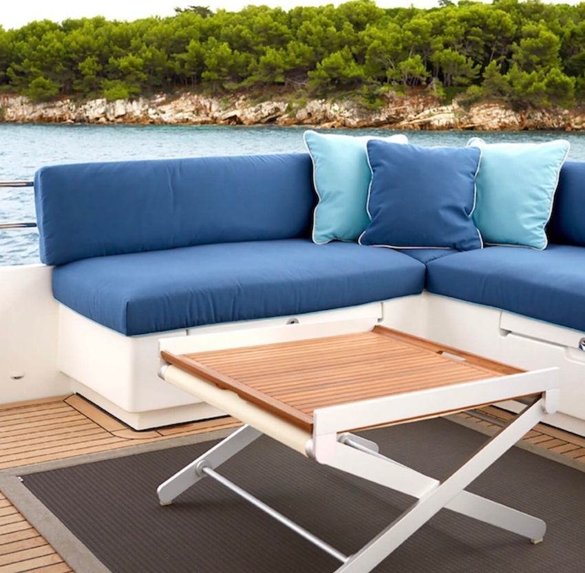 Banquette de bateau blanche avec assise bleu outremer et coussins Sunbrella camaïeu de bleu face à la mer.