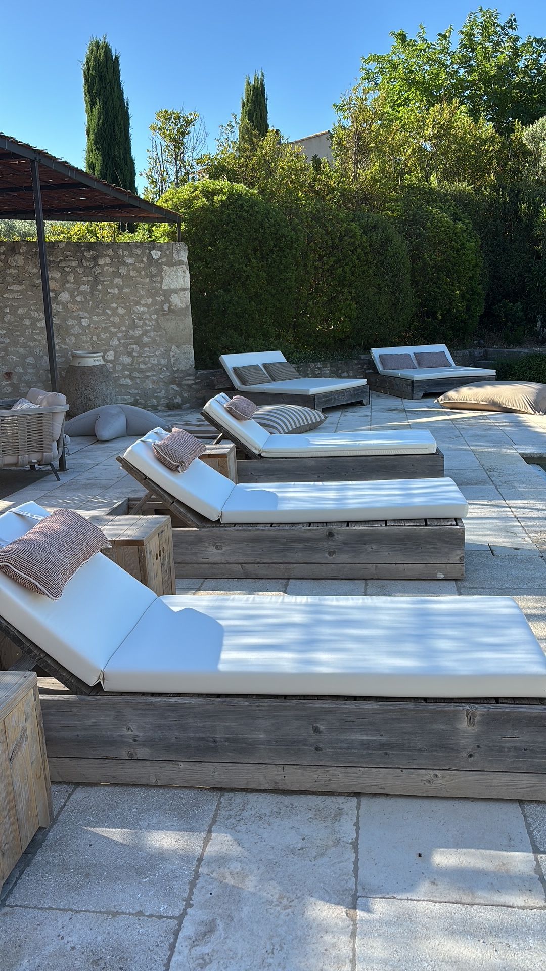 Ensemble de matelas extérieurs gris clair sur mesure pour une rangée de transats en bois au bord de l'eau.