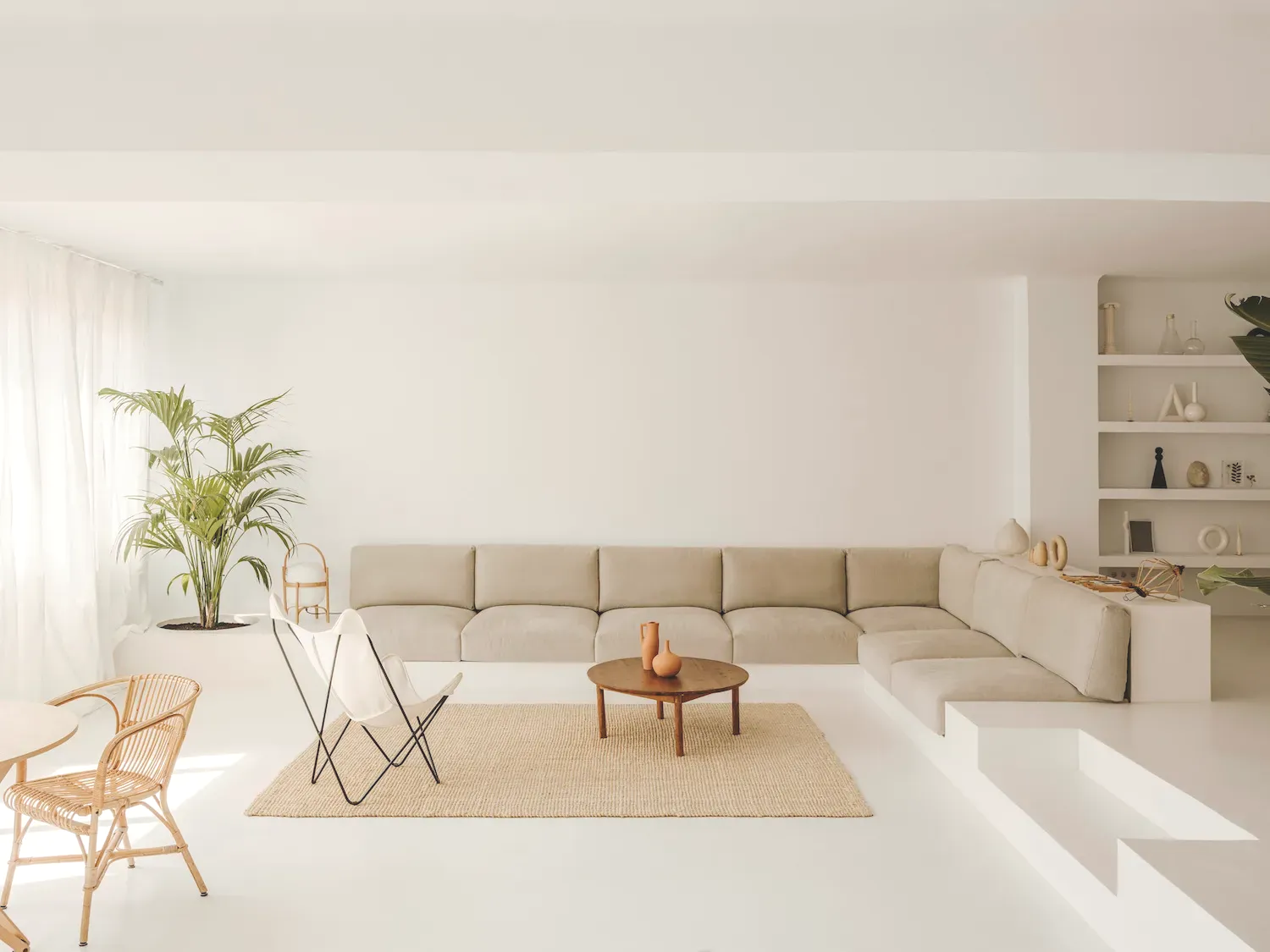 Grand salon moderne avec canapé d'angle beige lin et coussins déco dans un espace lumineux d'inspiration nordique.