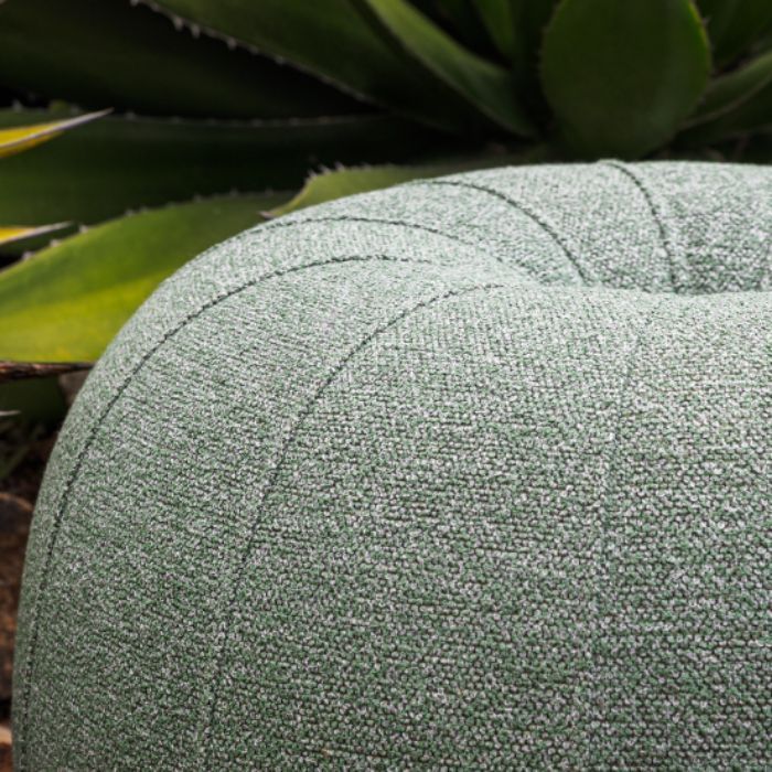 Gros plan sur une assise ronde en tissu bouclé vert sauge Agora Signature dans un jardin.