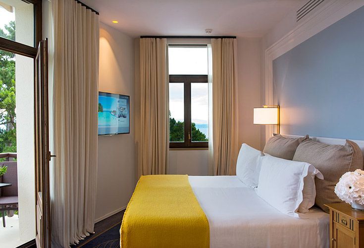 Tête de lit rembourrée beige et chemin de lit jaune moutarde sur mesure dans une chambre d'hôtel élégante.