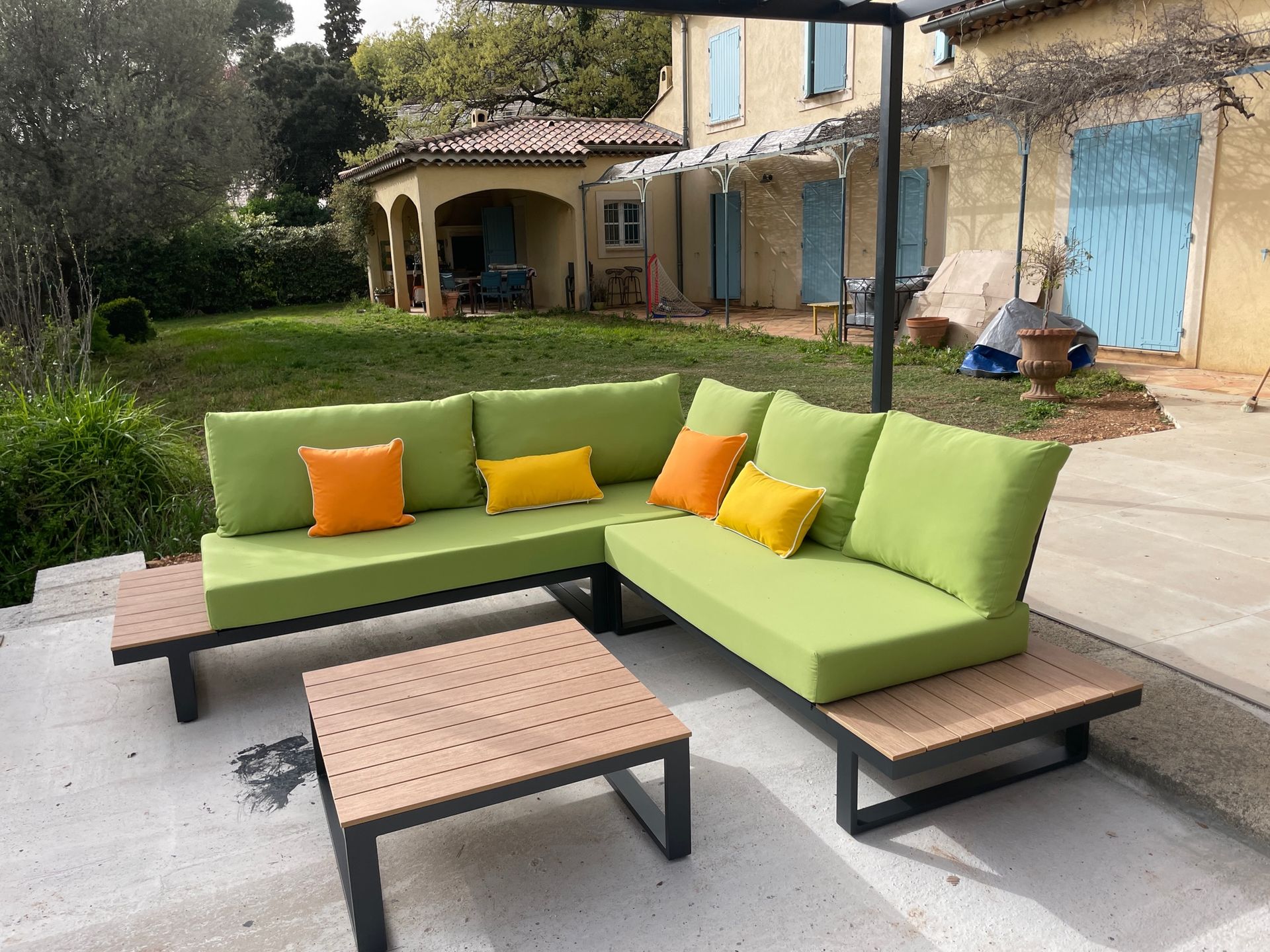 Coussins verts vifs sur mesure pour l'aménagement d'un canapé de jardin d'angle à structure métallique noire.