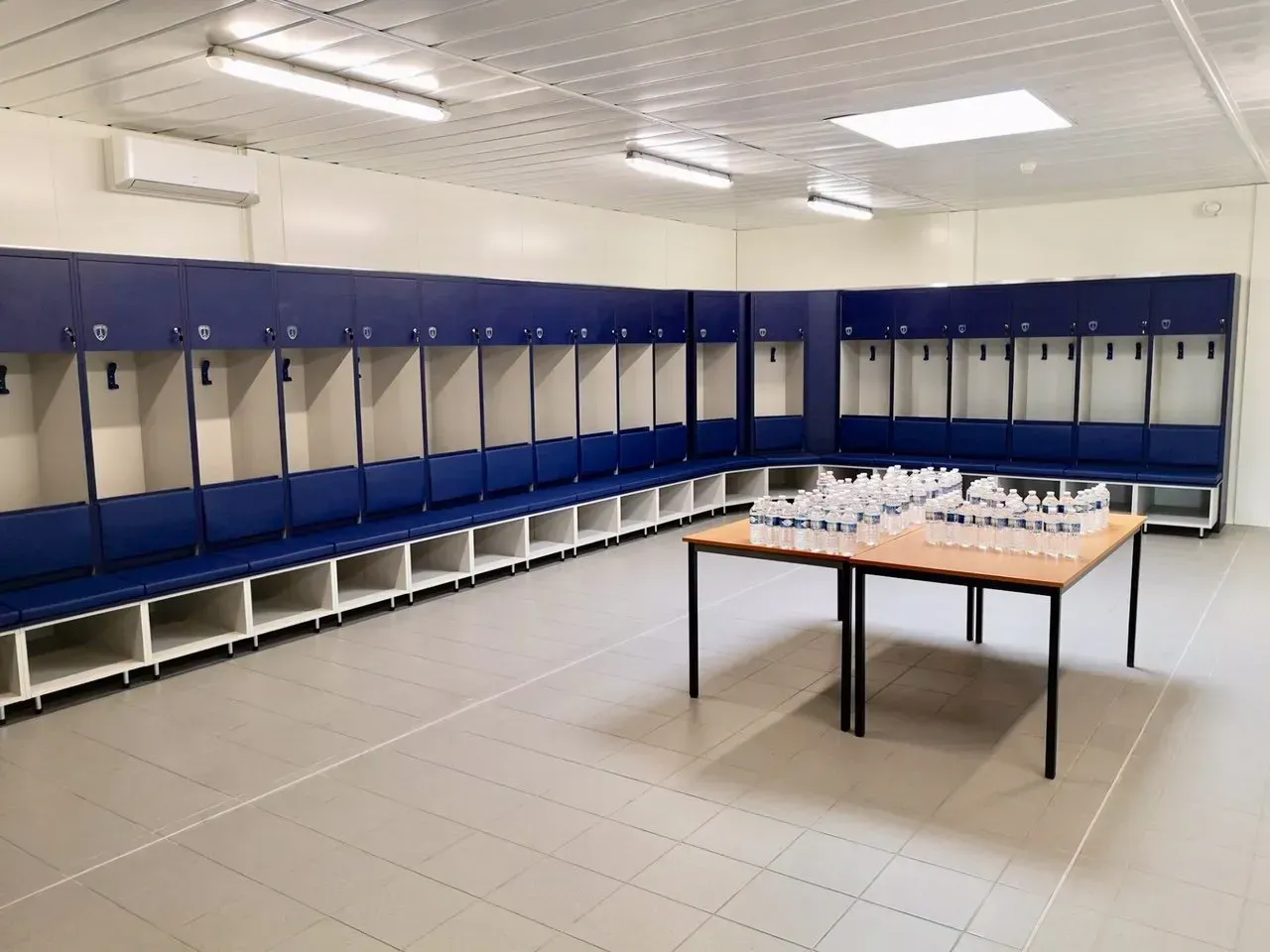 Longs coussins de banquette bleus sur mesure pour l'aménagement d'un grand vestiaire sportif.
