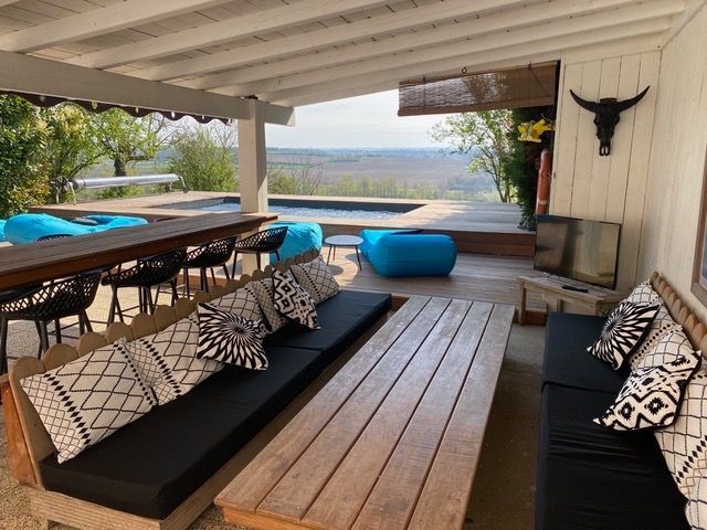 Longs coussins d'assise noirs sur mesure pour une banquette en bois avec vue panoramique sous terrasse couverte.