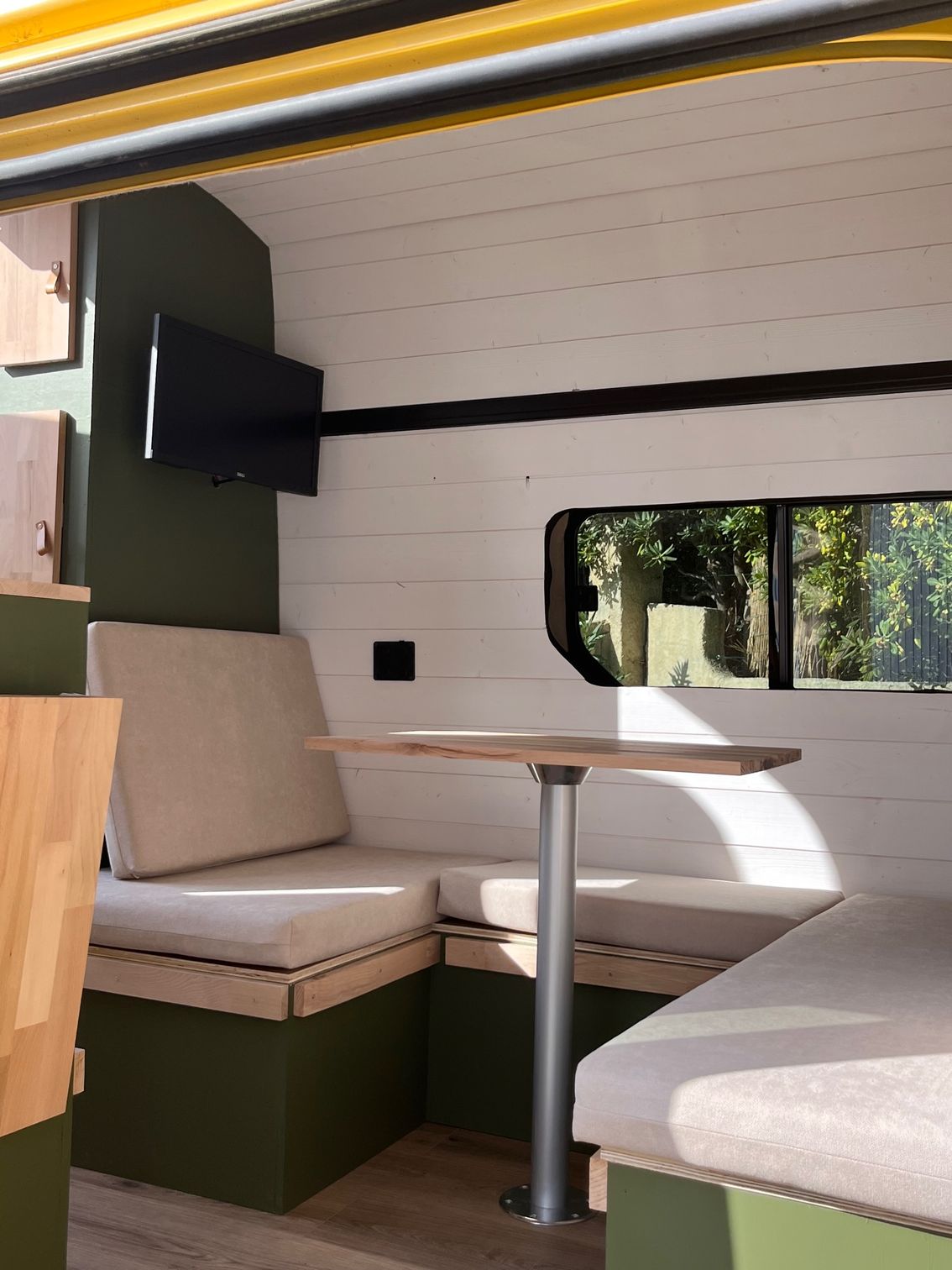 Aménagement van avec couchette et table centrale, coussins sur mesure tons beige et vert – Mousse et Confection