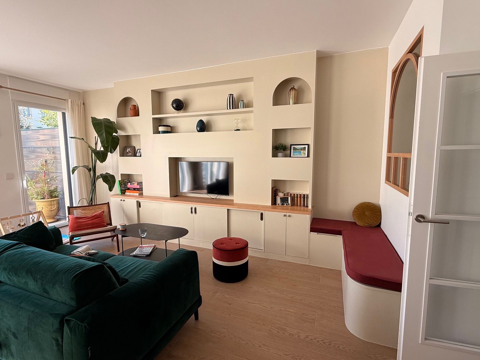 Coussin de banquette sur mesure rouge bordeaux épousant une structure arrondie dans un salon.