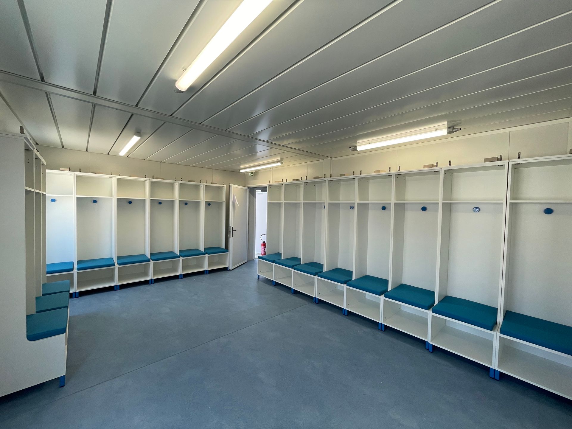 Coussins d'assise bleus sur mesure pour les bancs d'un vestiaire de football.