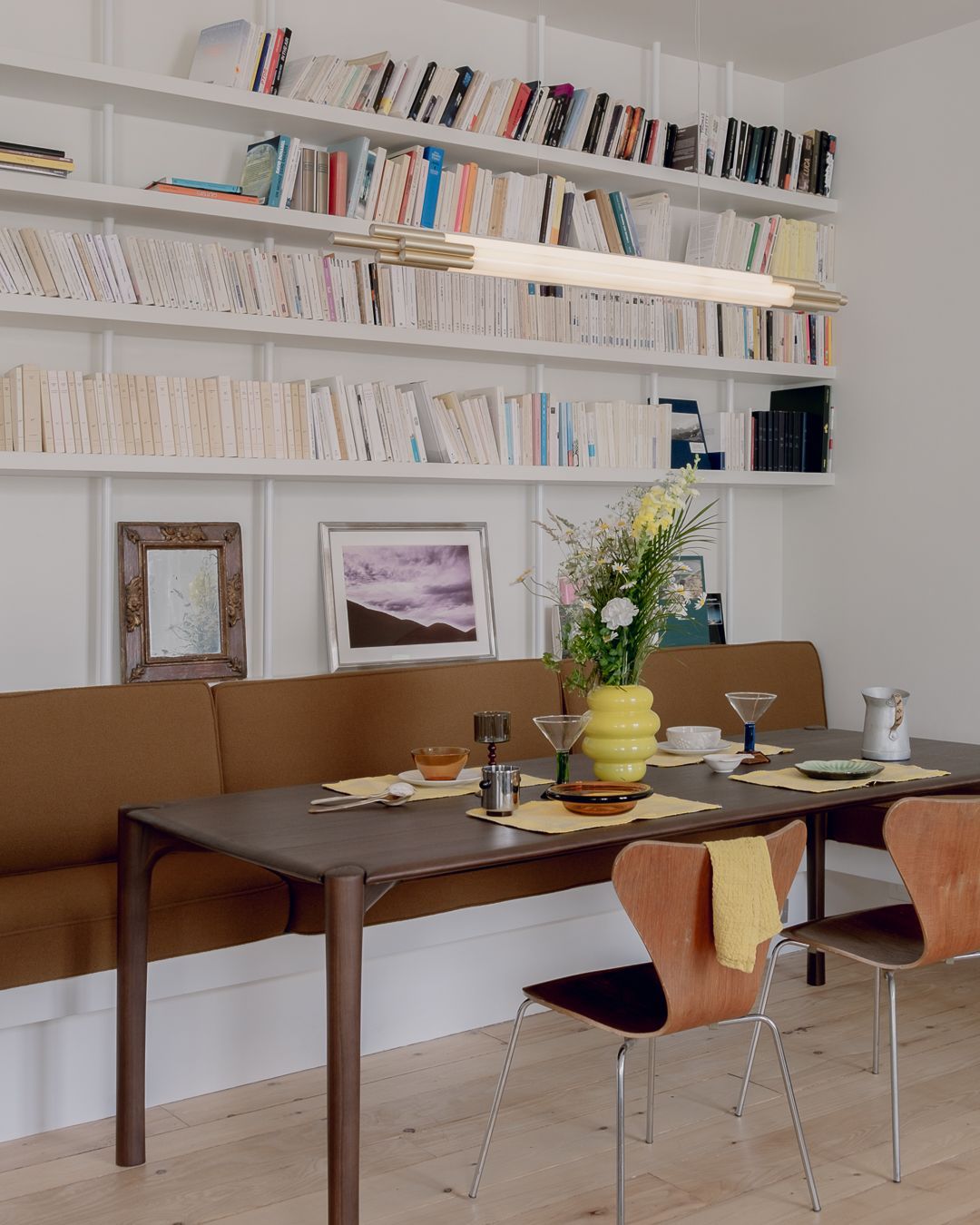 Grande bibliothèque blanche murale remplie de livres avec un luminaire design suspendu devant.