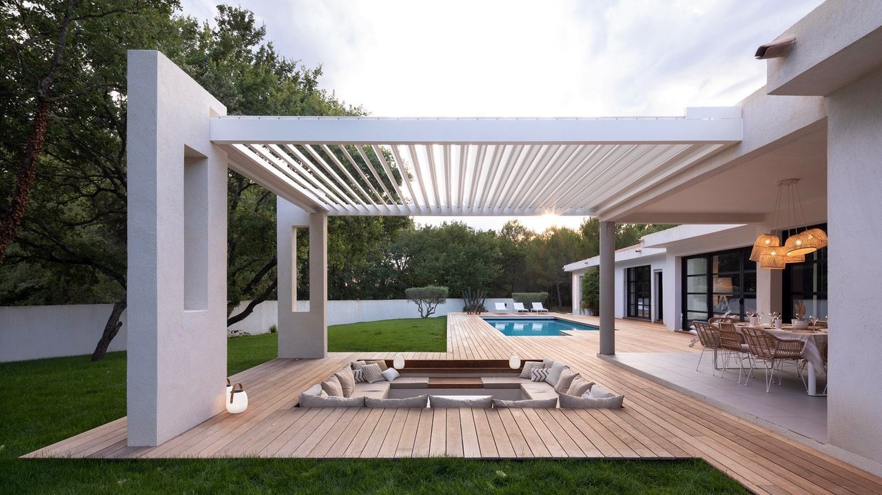 Grands coussins de sol extérieurs sur mesure disposés sous une pergola au bord d'une piscine.